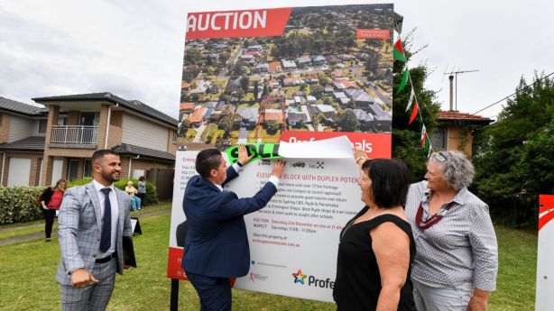 Sisters Jenny Lindsay and Louise Haverfield-Price help selling agents Paul Tassone and Ahmad Malas of Professionals Ermington put up the sold sticker for 17 Woodward Street. Photo: Peter Rae.