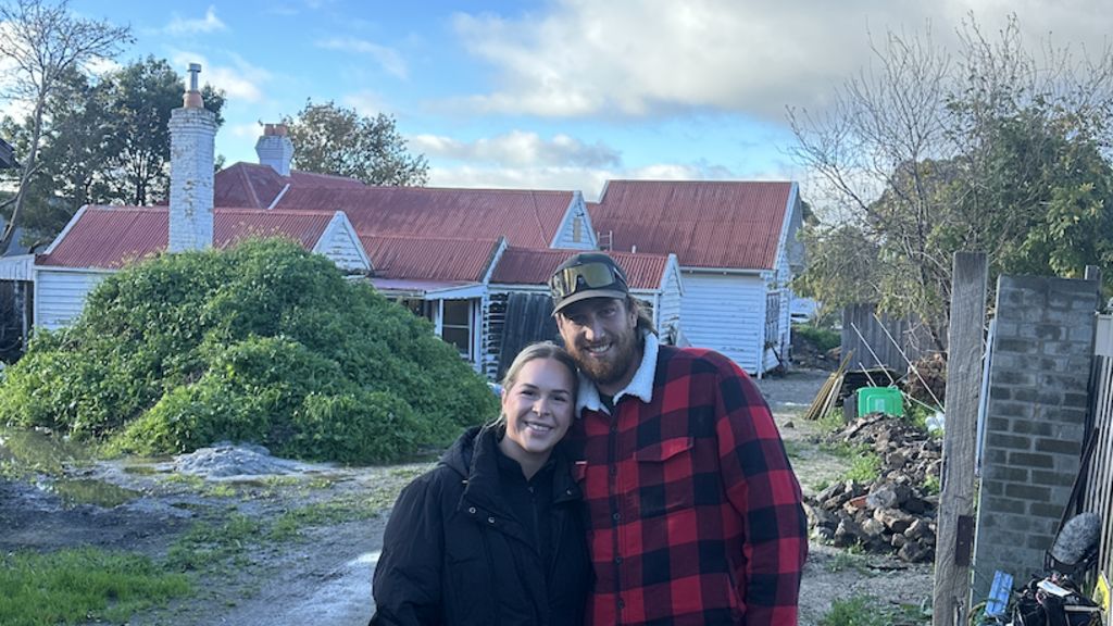 Ashlee and Tyson standing in front of their abandoned home.