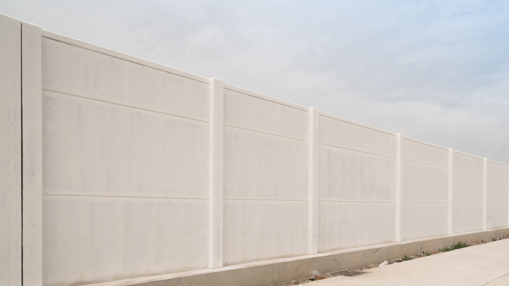 A stock photo of a white wall white fence concrete wall footpath
