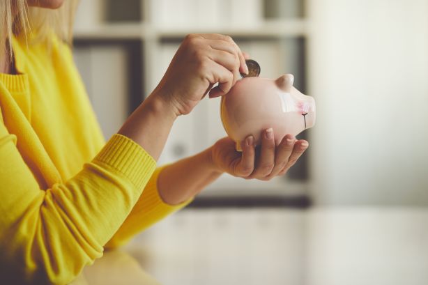 Woman inserts a coin into a piggy bank, toned image