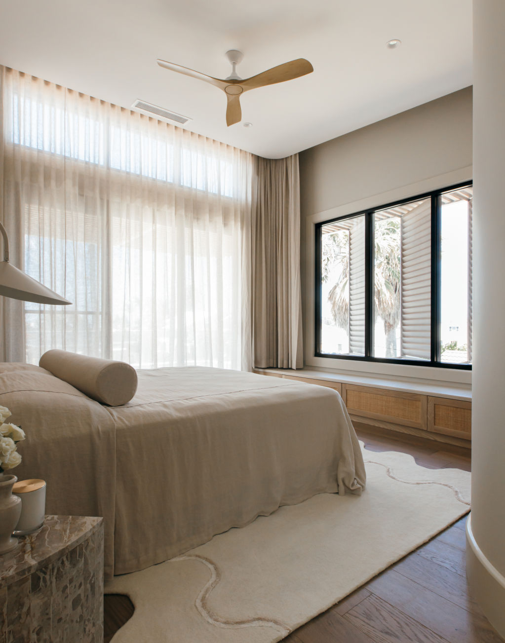The main bedroom in House One features cream tones and soft white linens and embraces curves. Photo: Grace Picot