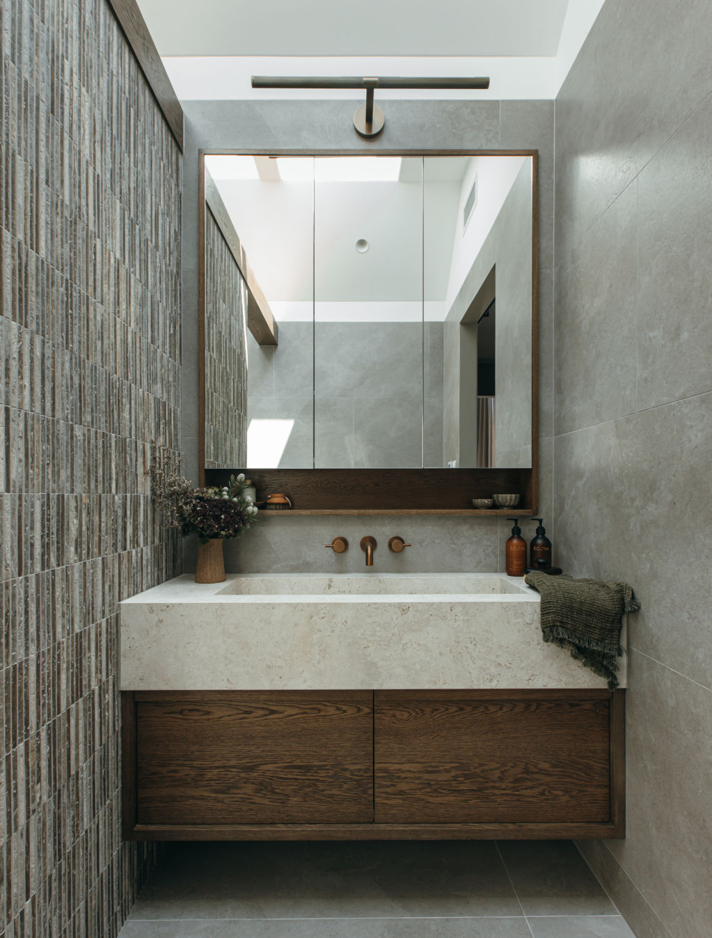 Dark travertine feature tiles and copper tapware give House Two’s en suite bathroom a calming, moody feel. Photo: Grace Picot