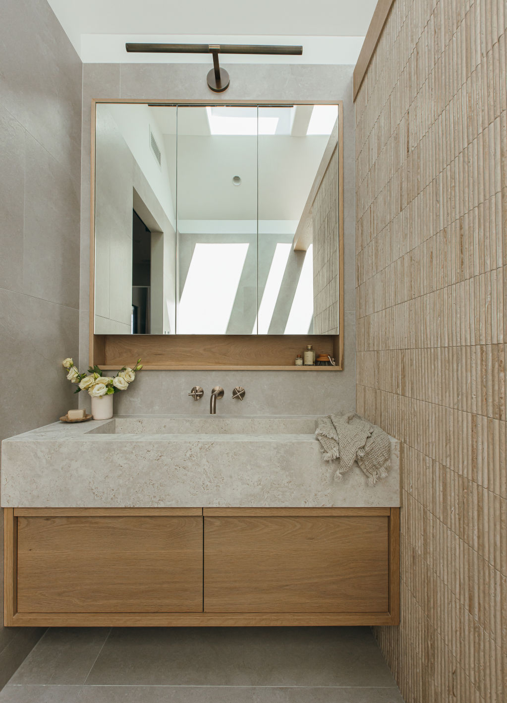 Light-coloured travertine feature tiles and champagne-hued tapware give House One’s en-suite bathroom a light, bright feel. Photo: Grace Picot and Kyal and Kara