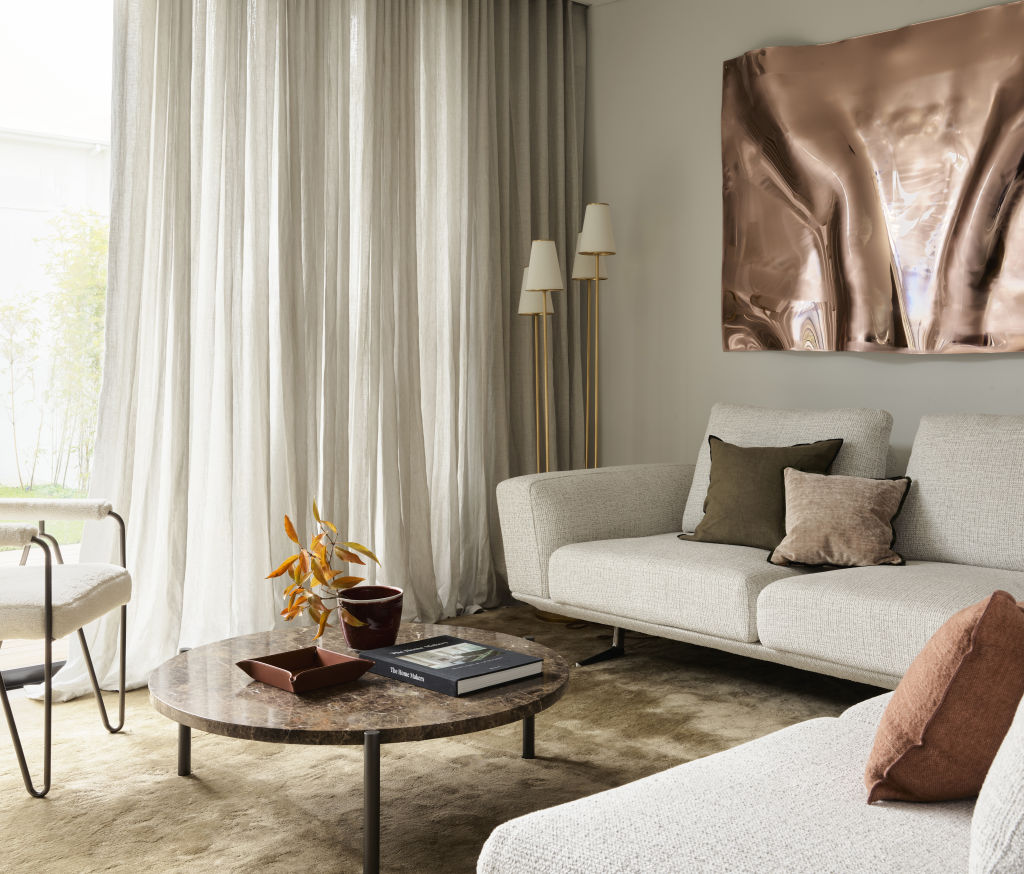 The living room is dressed in designer pieces, finished with an artwork from Anya Pesce. Photo: Supplied