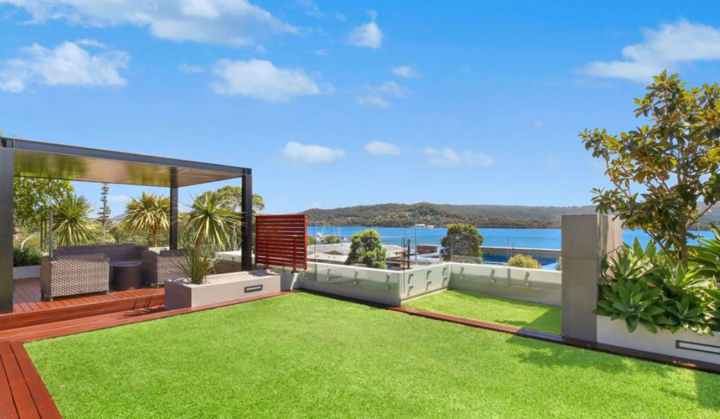 The large outdoor living area is equipped with a grassy lawn and a covered deck area. Photo: LJ Hooker Terrigal