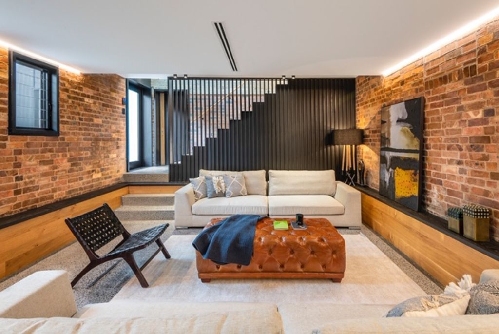 The lower level contains a rumpus room with exposed brick walls, timber bench seating and polished concrete floors. There is also a bedroom with exposed brick walls on this level. Photo: Adcock Prestige.