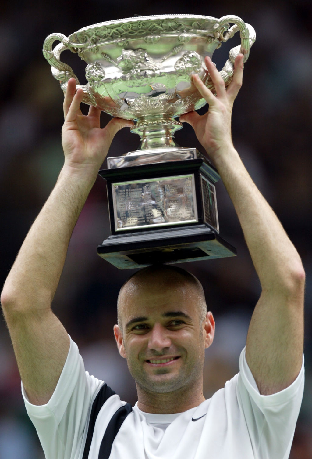 Andre Agassi proudly displays the winner's trophy aloft after his men's singles final victory Australian Open Tennis Championships in 2003. Photo: Rick Stevens.