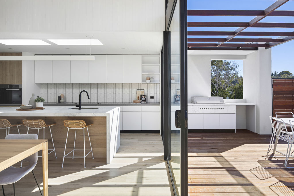 The open-plan kitchen flows out to a deck and pool. Photo: Supplied