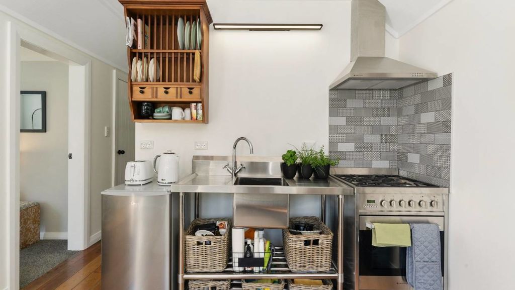 The unfitted kitchen features a stainless steel bench with integrated sink, and stainless steel oven. Photo: Lowe &amp; Co Realty