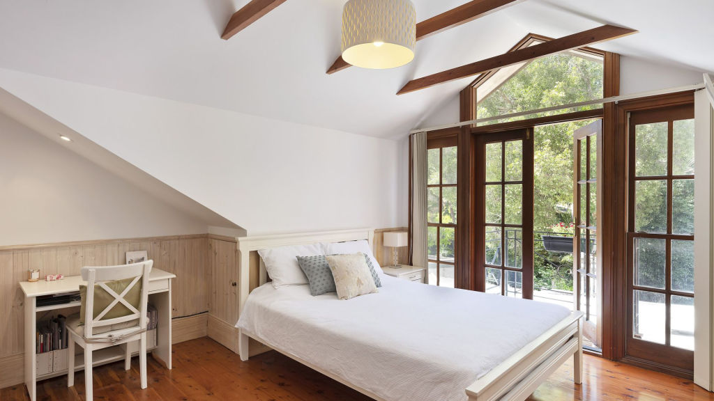 Timber is a highlight in this bedroom, from the exposed beams to the polished floors. Photo: Supplied