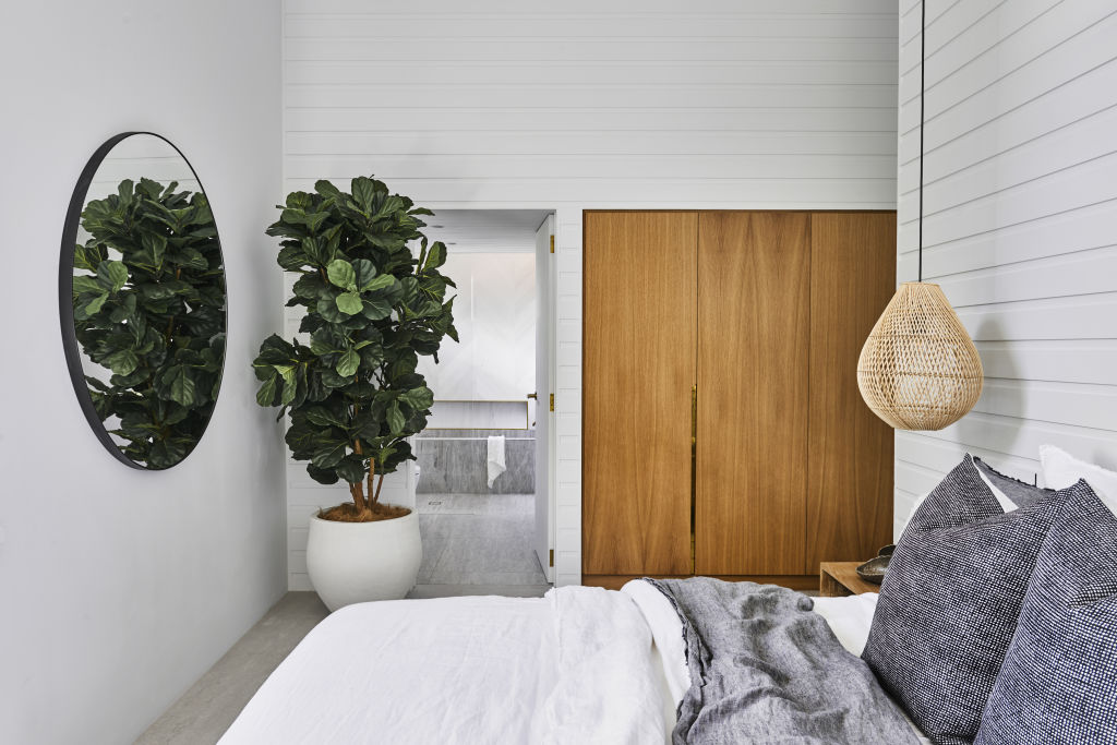 The master bedroom through to the ensuite. The family wanted to keep the house minimal to allow pops of greenery and timber detailing to feature. Photo: Nikole Ramsay