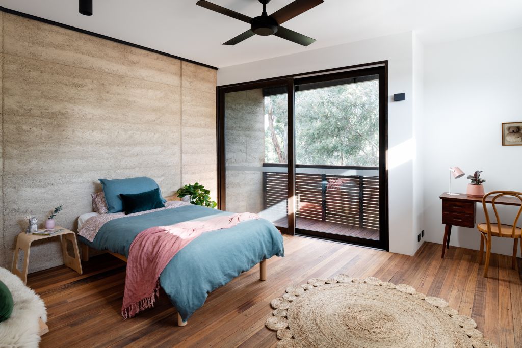 The rammed earth facade makes its way into one of the bedrooms. Photo: Jellis Craig