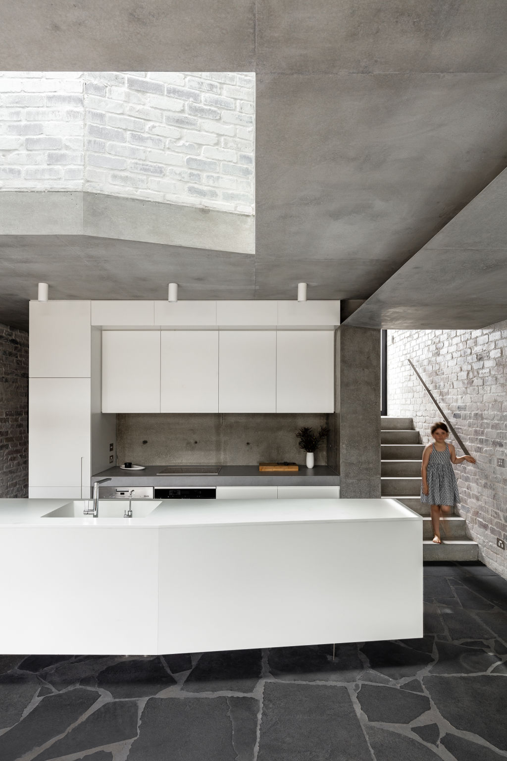 The void above the kitchen shows up the monotonal texture of the interiors. Photo: Tom Ferguson