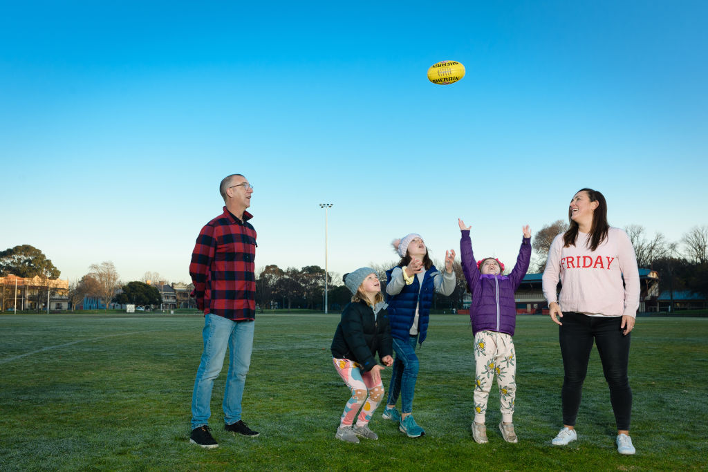 Emma Race and Andy Maher with their children Millie, 9, Sophie, 8 and Phoebe, 5, brushing up on their footy skills at Brunswick Street Oval. Photo: John Donegan 1826