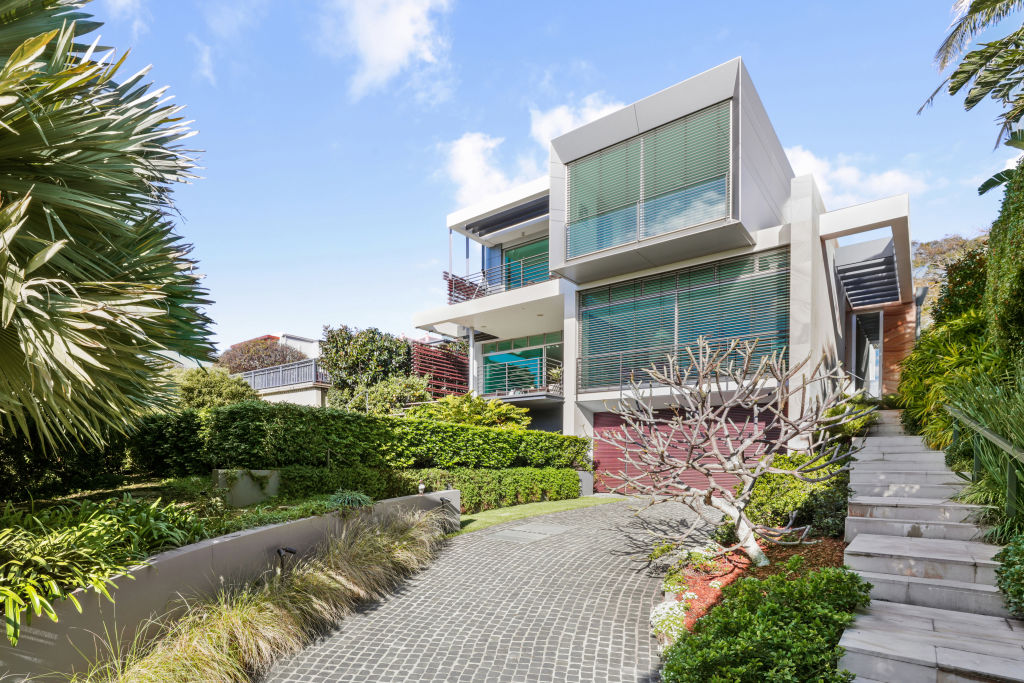 The facade is minimalist and clean in its design, framed by hedges and a frangipani tree. Photo: Supplied