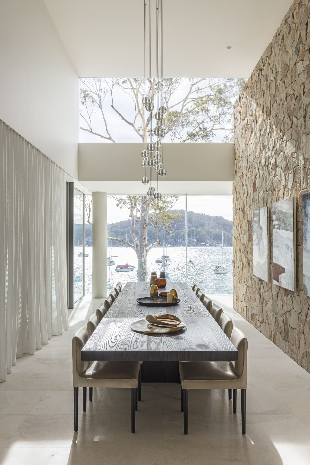 There is a sandstone feature wall at the centre of the home, and walls of glass overlooking Pittwater from every level. Photo: Supplied