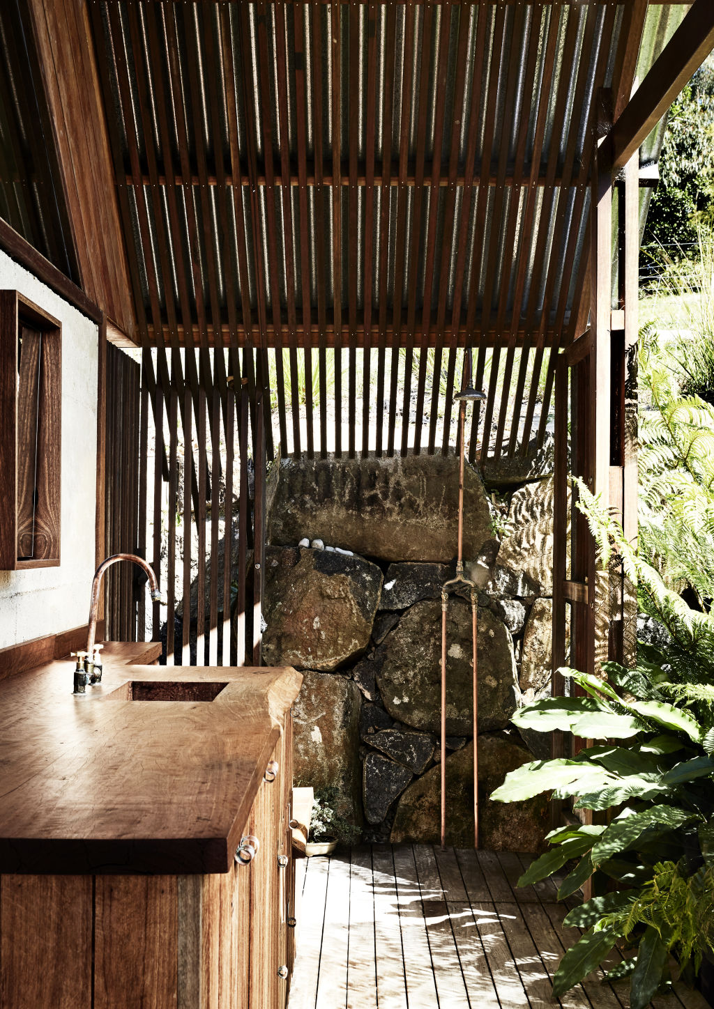 The outdoor bathroom/laundry which looks into a lush garden encircled by a stone retaining wall built from locally sourced columnar basalt. Styling: Annie Portelli. Photo: Caitlin Mills