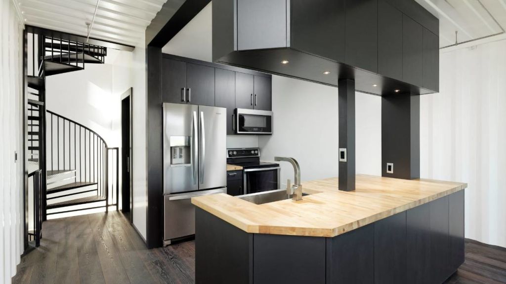 The open kitchen features double-sided cabinetry, a large handmade butchers block counter built around a modern self-trimming sink with Moen hardware. Photo: Supplied