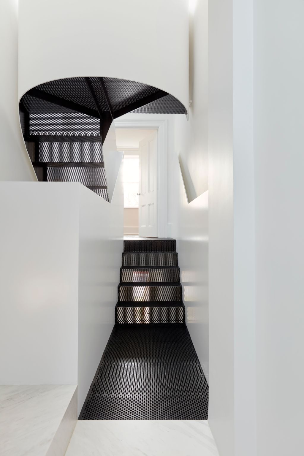 Winding up to the attic room, the perforated staircase is shaped as a sculptural ribbon. Photo: Tom Ross