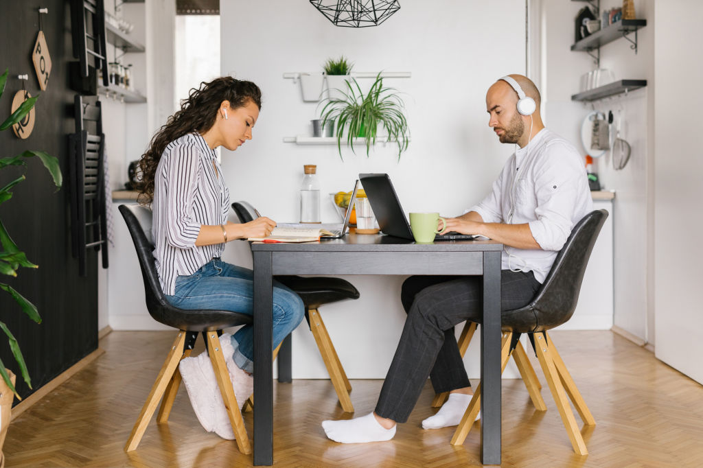 Young married couple working from home, they are sitting in their dining room.