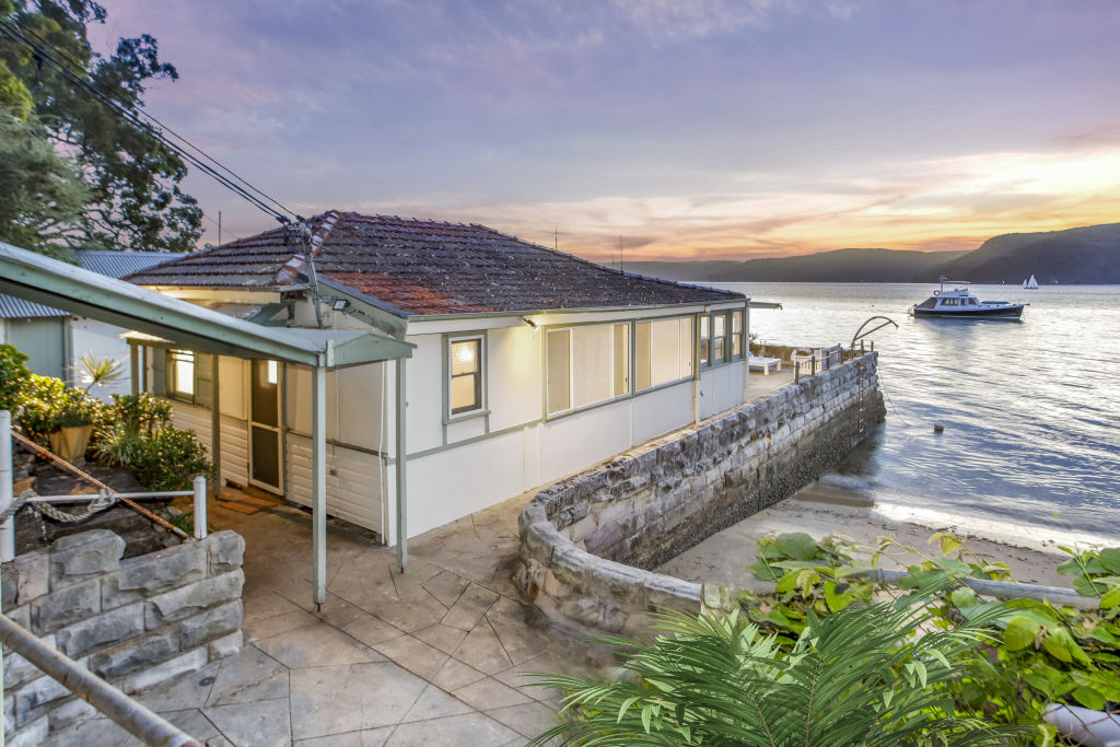 The three-bedroom cottage is built out over the water, leaving much of the 936 square metre parcel as bushland.