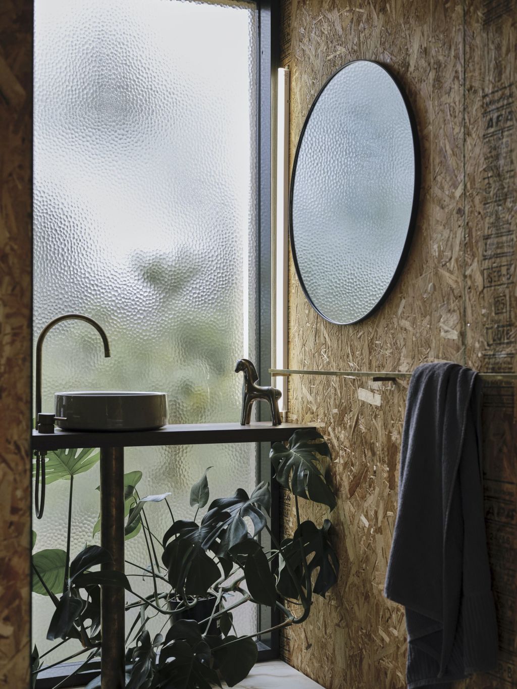 With a full-height dimpled-glass window, the texture of SIPS wall and the sculptural basin, the bathroom is a moment of delight. Photo: Adam Gibson