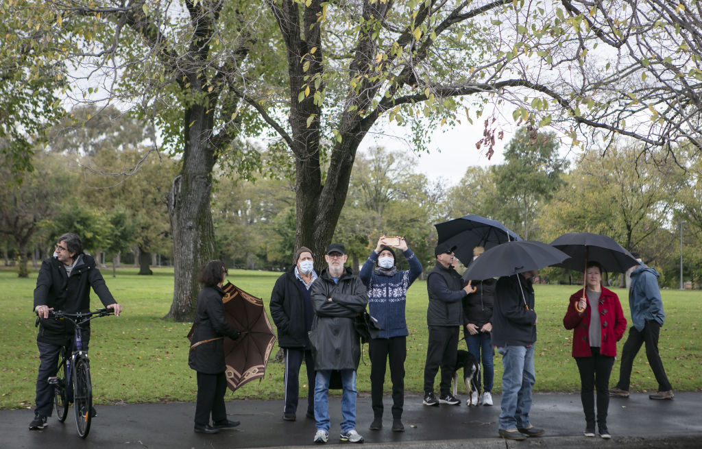 Onlookers huddle under umbrellas but fail to raise their hands at the auction of a National Trust-listed home in Clifton Hill on Saturday. Photo: Stephen McKenzie
