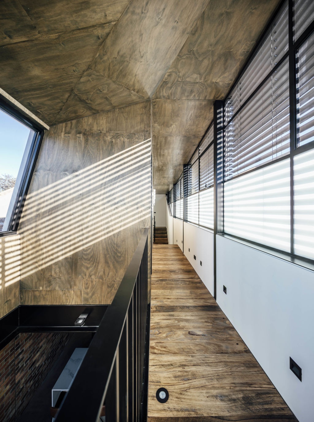 Recycled floors and fascinating shadow-play animate the upper hallway. Photo: Michael Kai