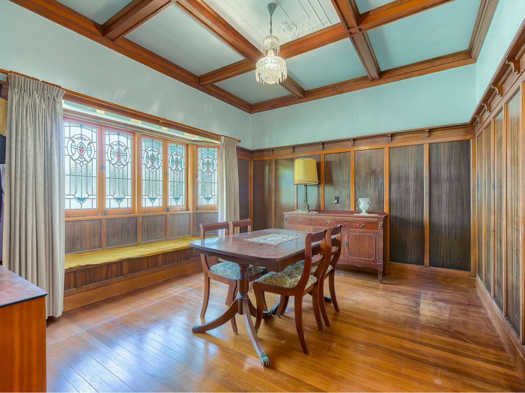 The dining room of 15 Chermside Street, Highgate Hill, features wood panelling and lead light windows.