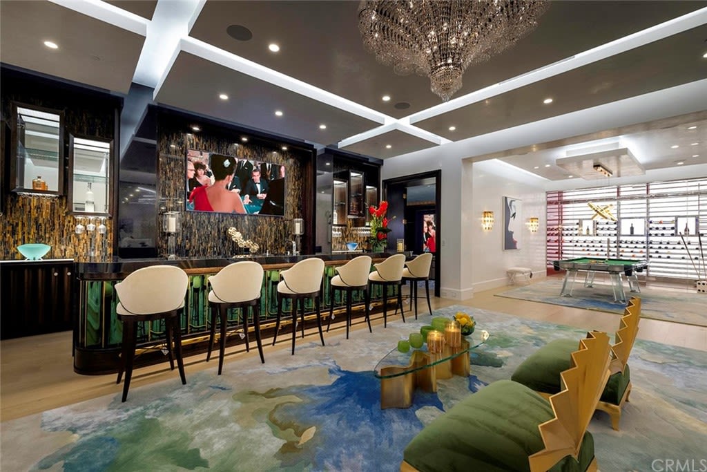 An entertaining lounge features a green-glass-tiled bar and a pool table made of glass.