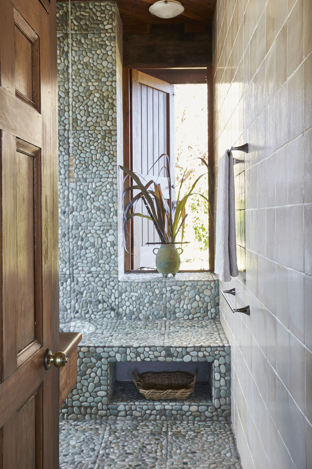 The main bathroom is finished with river pebbles and a sliding door that leads to the courtyard. Photo: Supplied