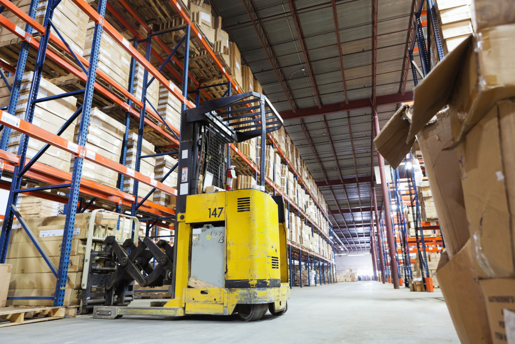 Forklift truck in shipping distribution warehouse lined with boxes
