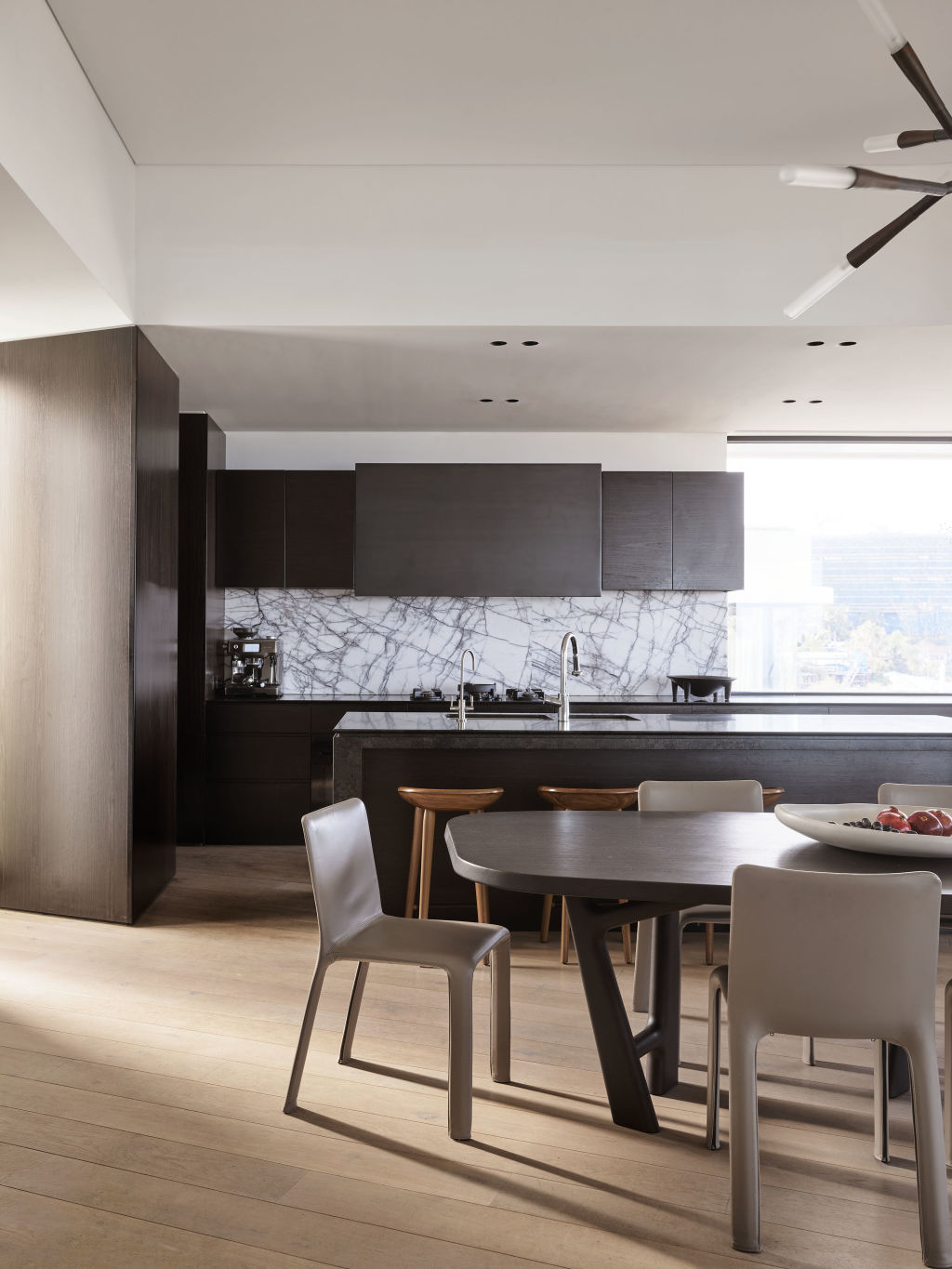 The kitchen is the heart of the home and is a melee of finishes from dark-stained timber veneer to New York marble and brushed granite. Photo: Anson Smart
