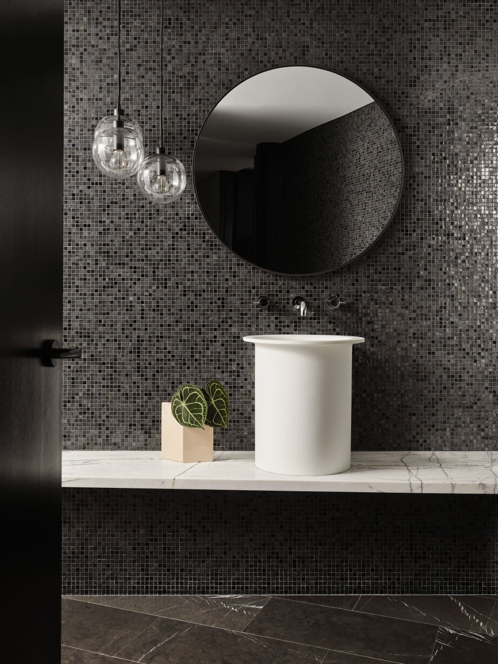 A powder room imagined in New York stone and black mosaics acts like jewellery for the home.  Photo: Anson Smart
