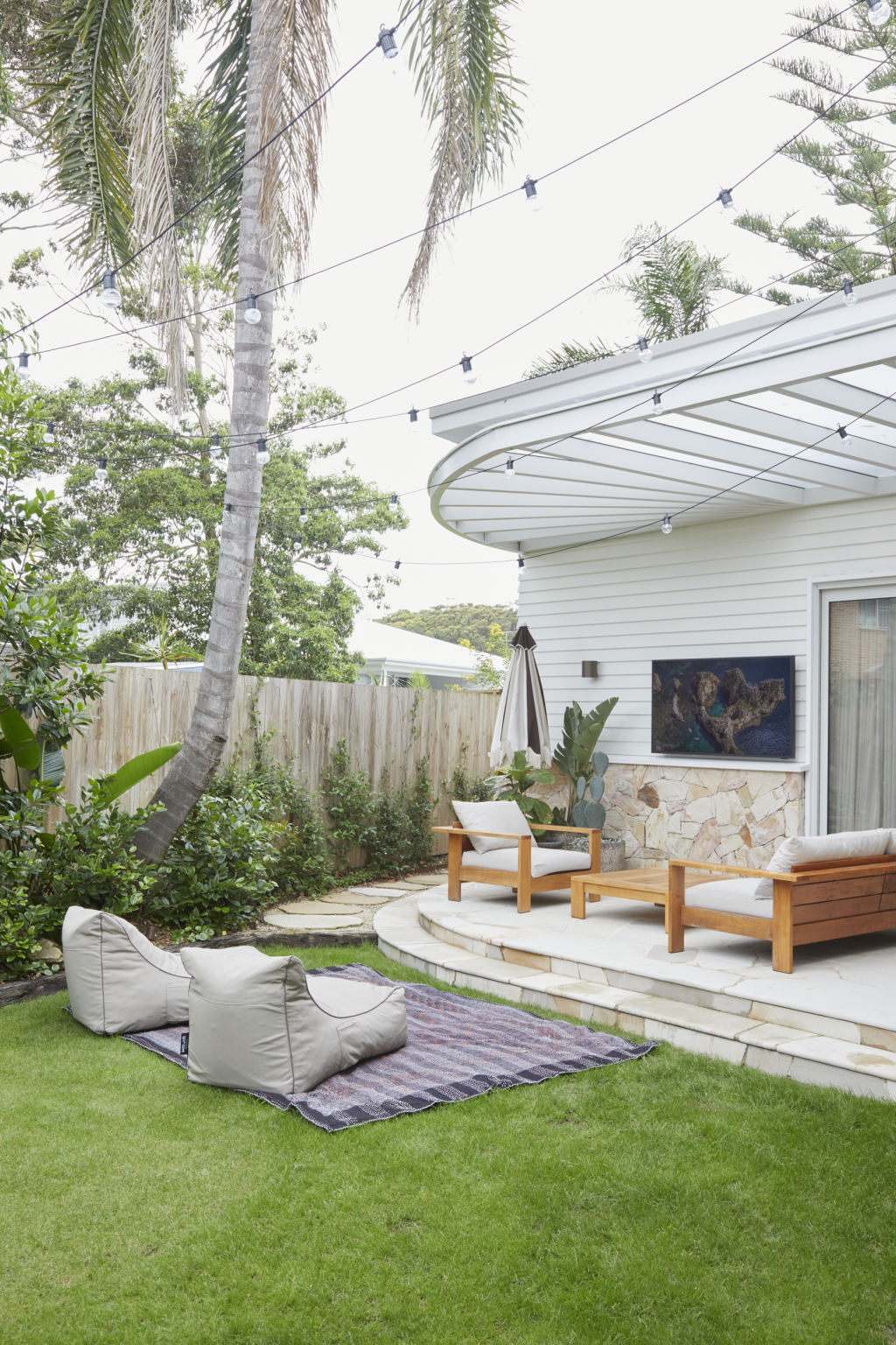 The couple love versatile indoor-outdoor living, so have seamlessly linked the living and entertaining zone to the garden, pool and patio - complete with a Samsung Terrace Outdoor TV. Photo: Nicky Ryan