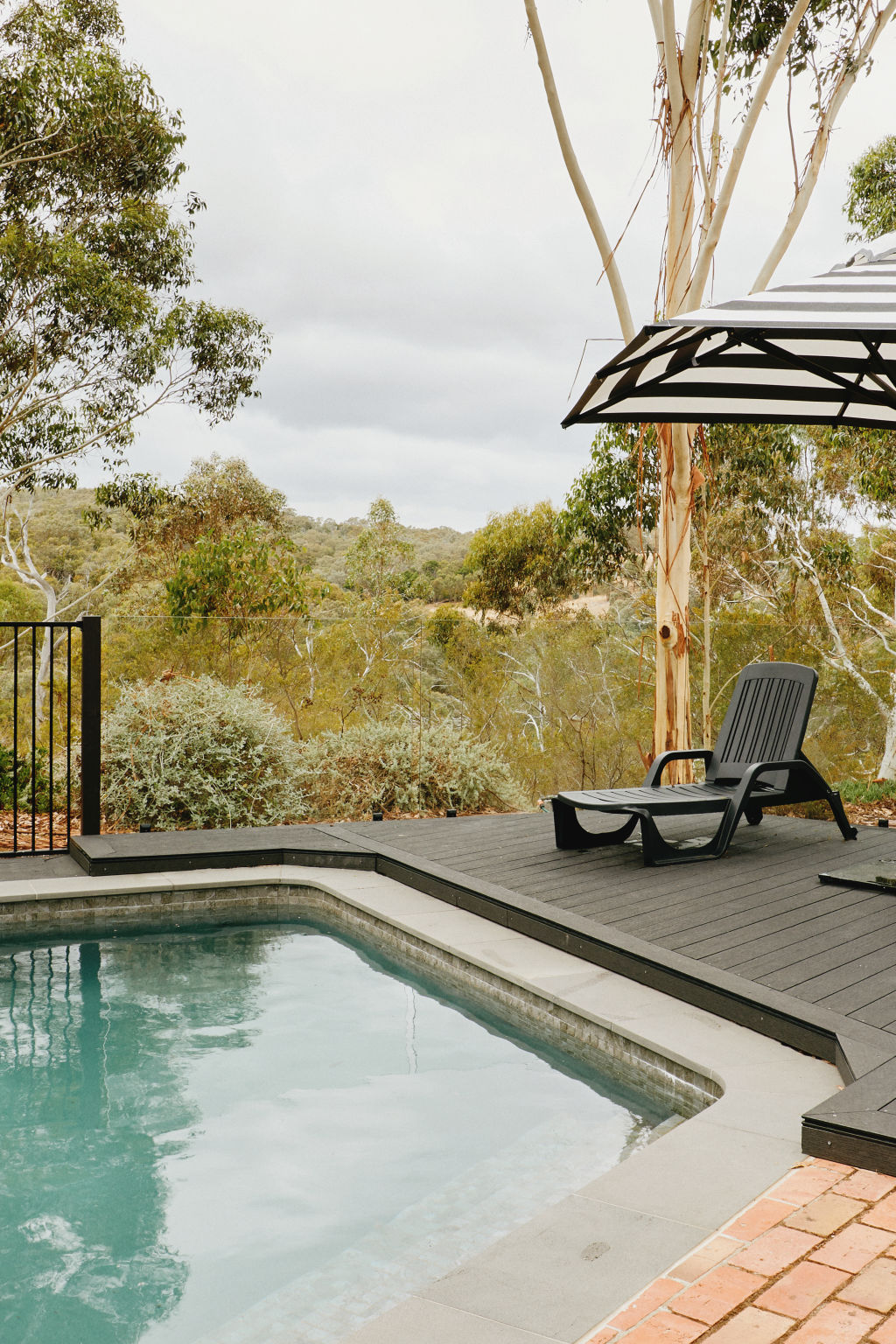 ‘Perched up on a hill, the property boasts some amazing views,’ Susie says. The large pool, which had been empty for years, was the first thing her family restored. It is edged in bluestone pavers and has a raised charcoal deck at one end. Sunranger Cafe Umbrella in ash black and white stripe from Shade Australia.  Styling: Annie Portelli. Photo: Amelia Stanwix