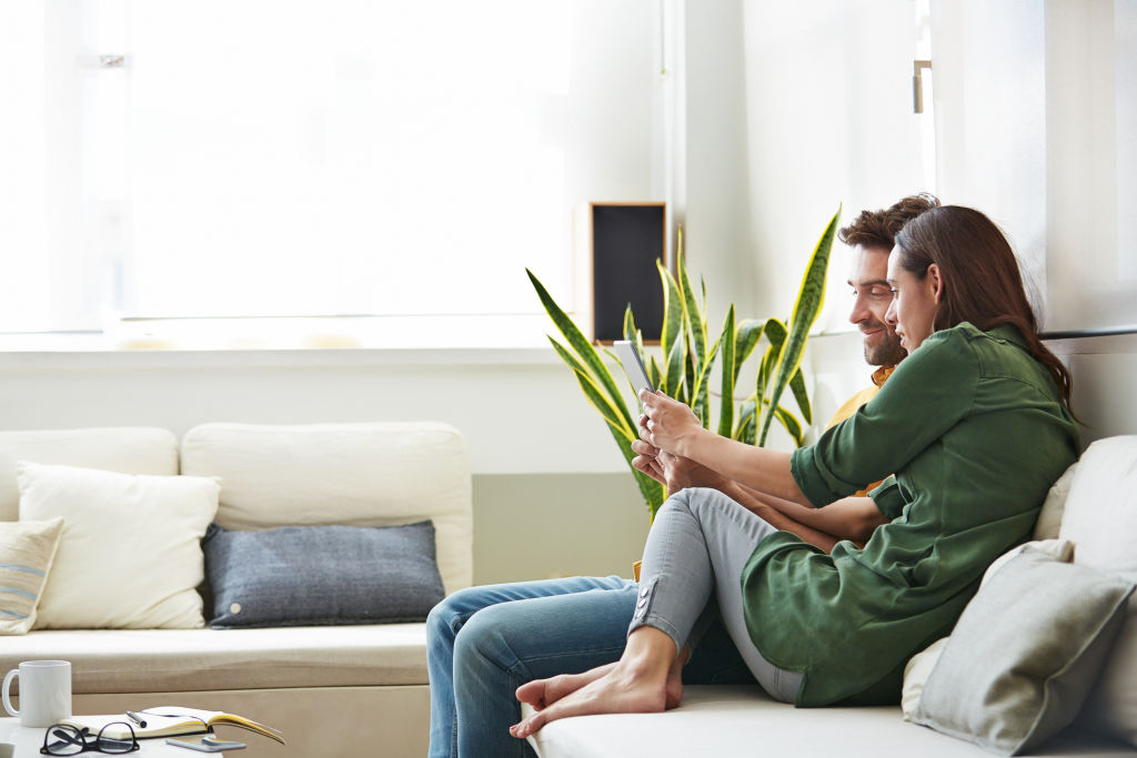 Shot of a smiling young couple using a digital tablet together while relaxing in their living room
