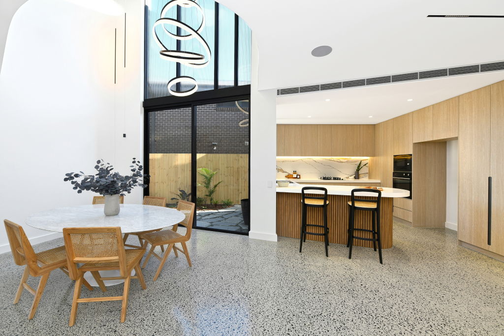 The kitchen features a curved stone benchtop, marble splashback and timber cabinetry. Photo: Supplied