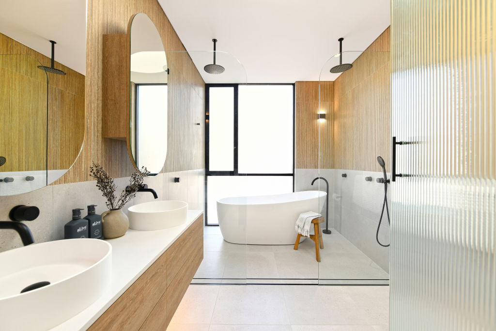 The en suite bathroom comes with backlit mirrors, a fluted glass door and dual rain showers. Photo: Supplied