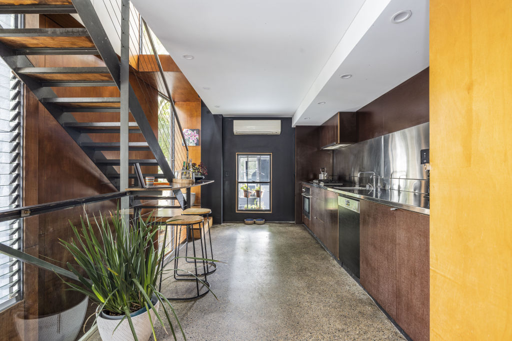 On the first floor, a stainless steel kitchen flows into an open dining and living space, with leafy park views. Photo: BresicWhitney