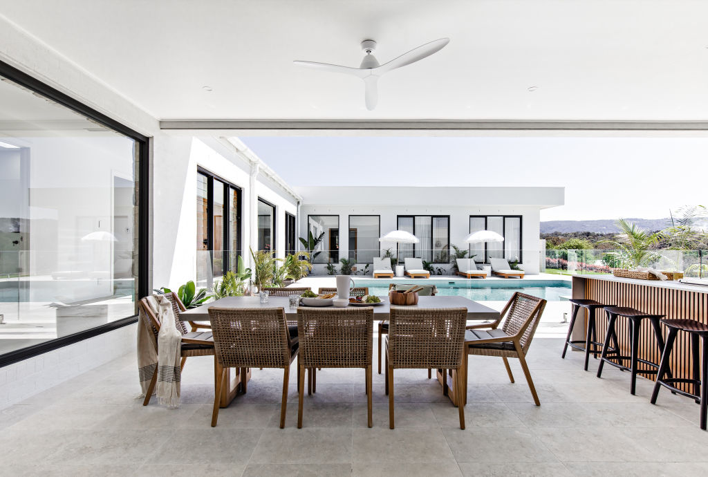 Glass-stacked doors open the dining and kitchen space to the pool seamlessly.  Photo: Supplied