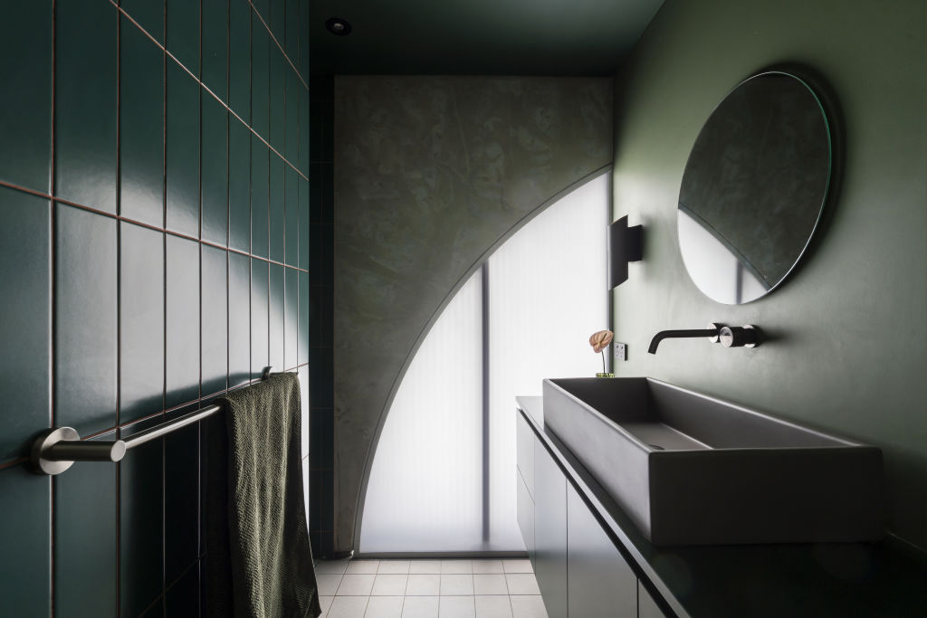 The deep forest green en suite is a pop of colour against the concrete palette. Photo: Supplied