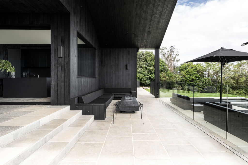 The home features black-stained ironbark cladding and distressed limestone flooring. Photo: Supplied