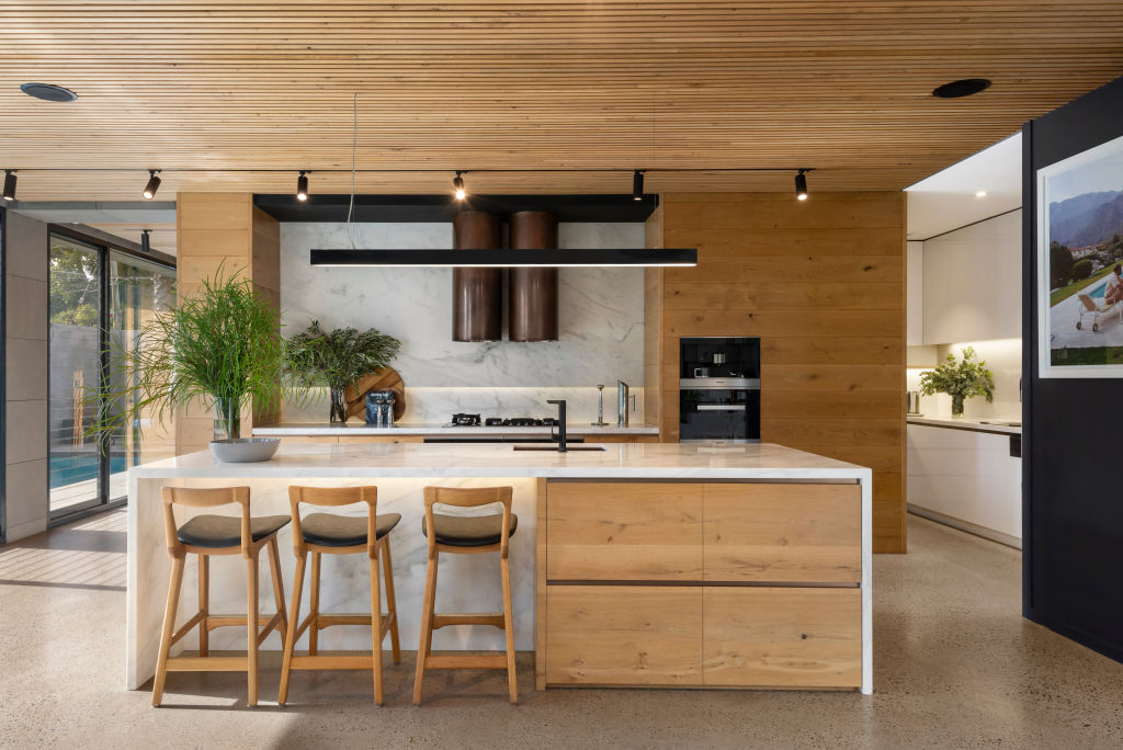 The white marble splashback and benchtops elegantly contrast the polished stone flooring in the kitchen.