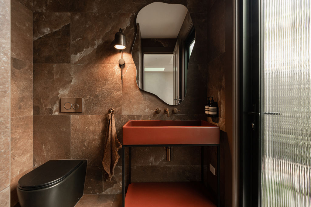 A vibrant, red clay basin and black toilet add impact in House Two's downstairs powder room. Photo: Grace Picot