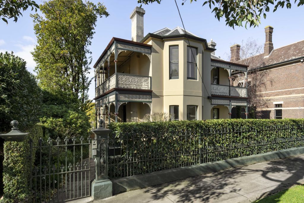 The period home is framed by wrought iron fencing and hedging.