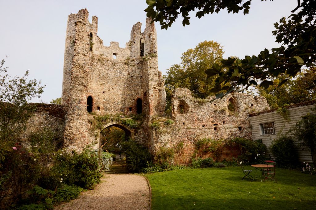 Ruined 14th century medieval castle in sunny garden.