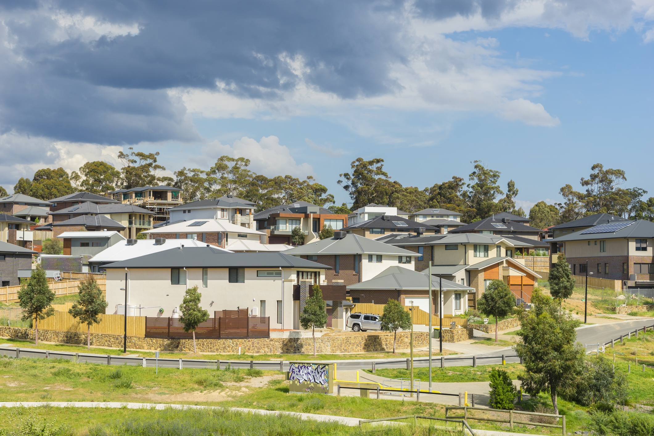 Row of new, modern suburban houses on the hill in Melbourne with trees during daytime.